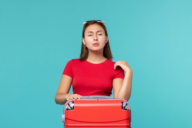 Front view young female with red bag getting ready for vacation on light blue space