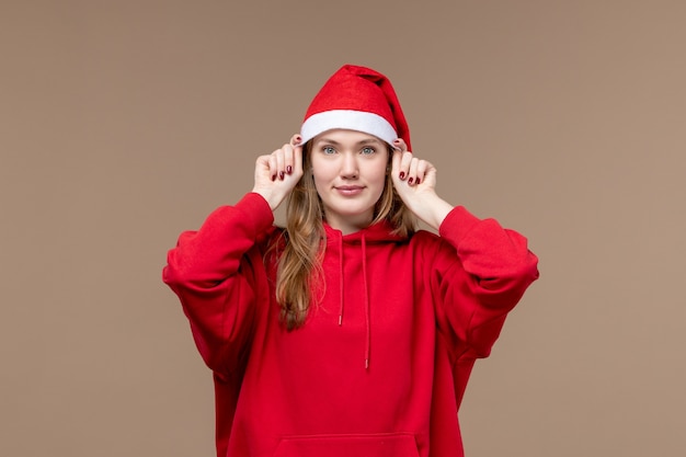 Free photo front view young female with red cape smiling on brown background christmas emotion holiday