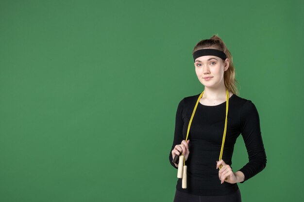 Front view young female with skipping rope on green