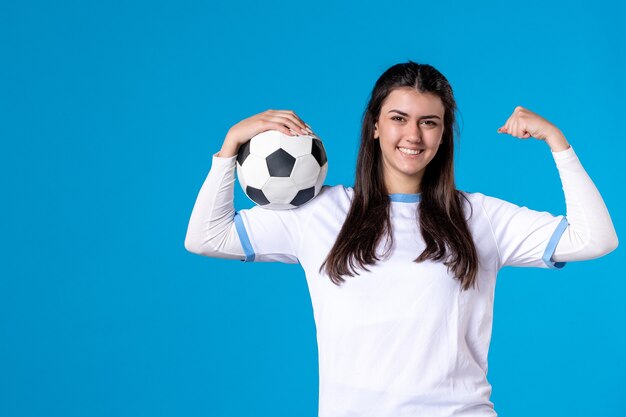 Front view young female with soccer ball on blue wall