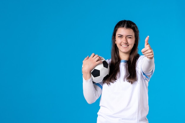 Front view young female with soccer ball on blue wall