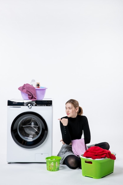 Free photo front view of young female with washing machine folding dirty clothes on a white wall