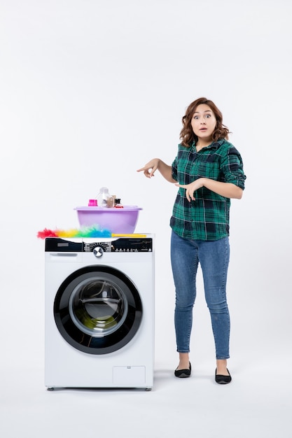 Front view young female with washing machine and shampoos on white wall