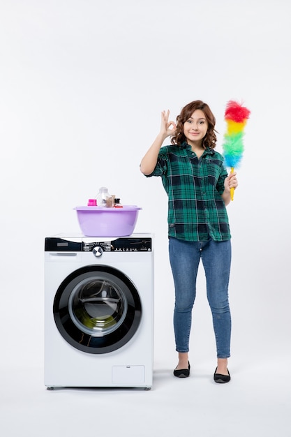 Free photo front view of young female with washing machine on white wall