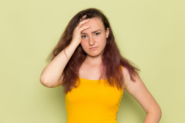 A front view young female in yellow shirt with depressed expression girl emotion headache