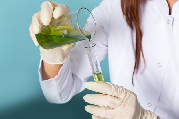 Front view of young feman chemist in white suit in front of table working with solutions