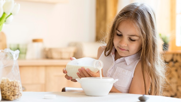 Free photo front view of young girl eating cereals for breakfast