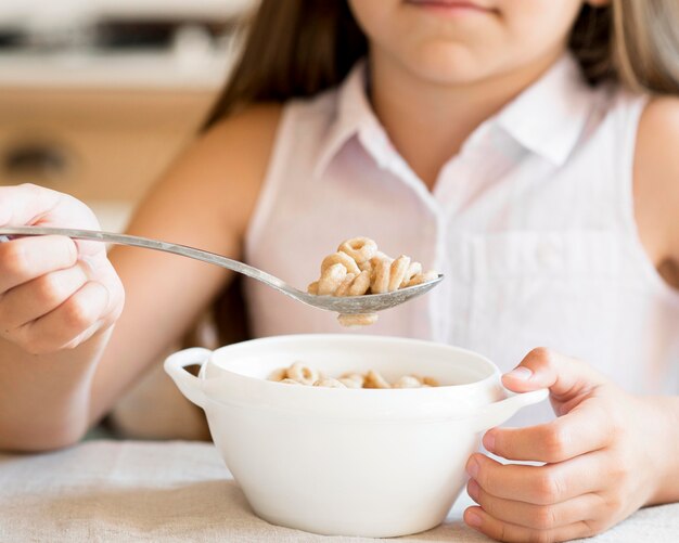 Front view of young girl eating cereals for breakfast