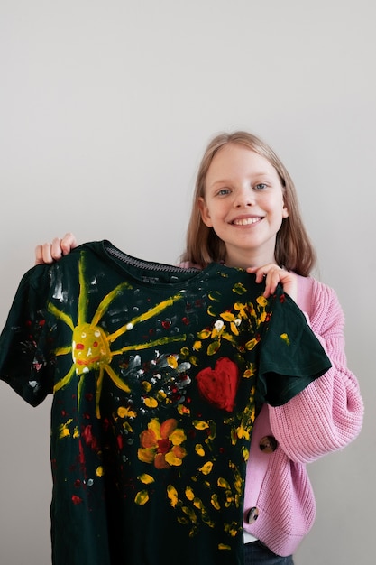 Front view of young girl holding diy painted t-shirt