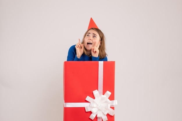 Front view of young girl inside red present box on white wall