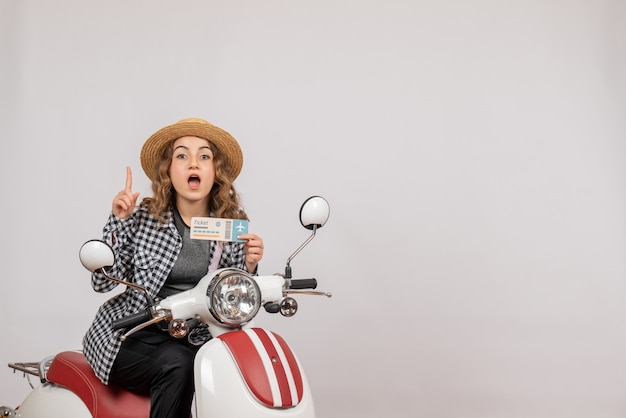 Front view young girl on moped holding ticket pointing finger up