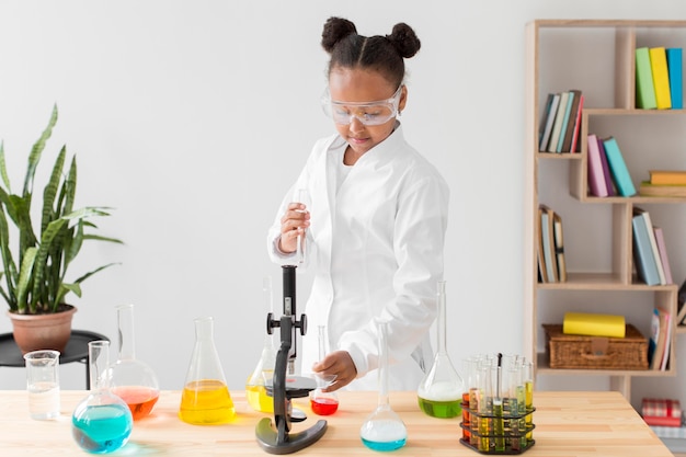 Free photo front view of young girl scientist in lab coat with potions