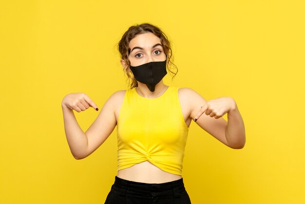 Front view of young girl in sterile mask on yellow wall