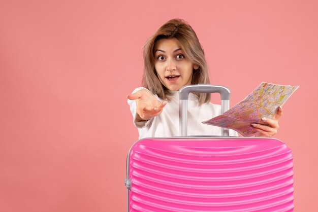 Free photo front view young girl with pink suitcase holding map reaching hand