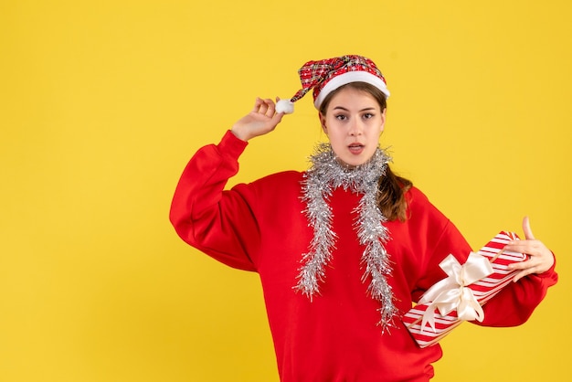 Front view young girl with red sweater holding gift and her santa hat