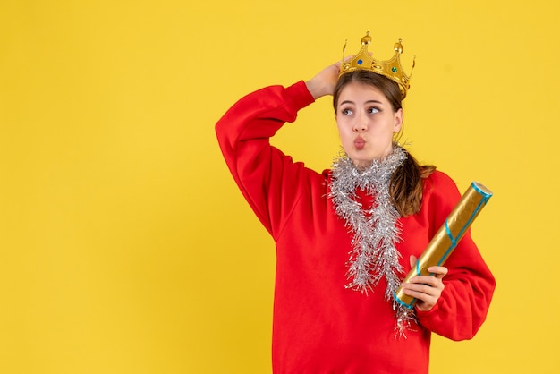 Front view young girl with red sweater holding party popper and her crown