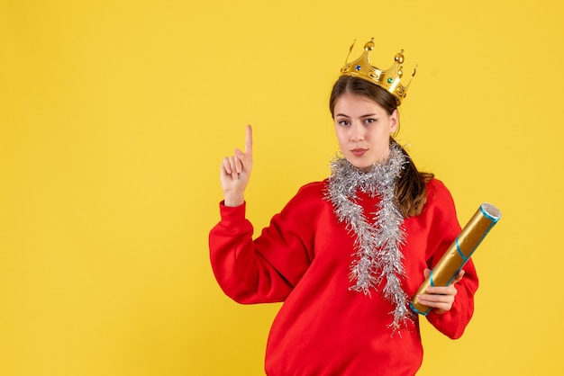 Front view young girl with red sweater holding party popper pointing with finger up