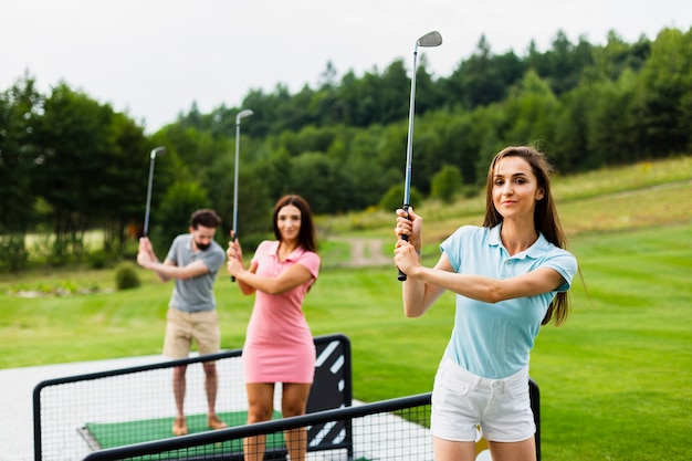 Free photo front view of young golfers with stick up