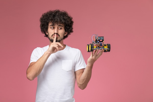 Free photo front view young guy showing keep silent gesture and electronic robot