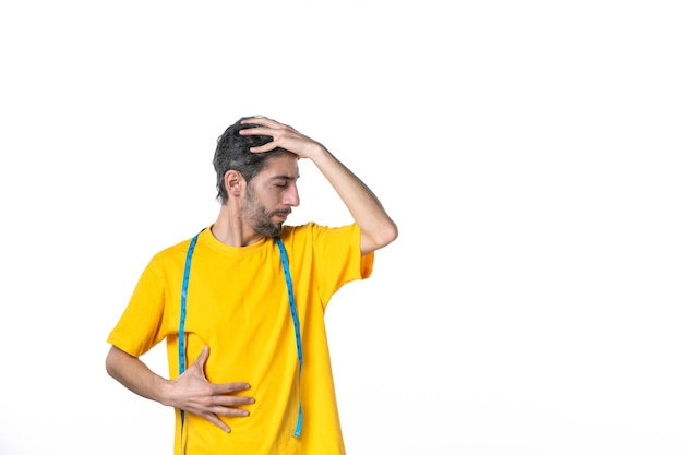 Front view of young guy in yellow shirt and holding meter feeling tired on white surface