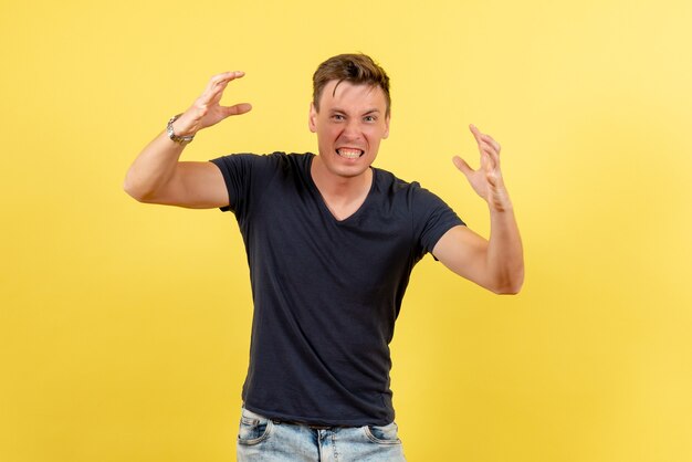 Front view young handsome male in dark t-shirt and jeans posing on yellow background male color model emotions human