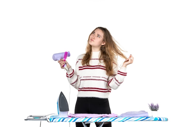 Free Photo front view young housewife holding brush and hairdryer on a white