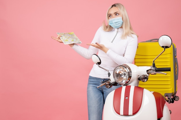 Free photo front view young lady pointing at map standing near moped