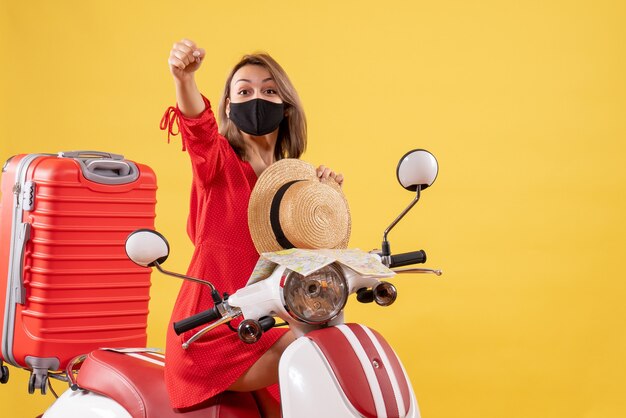 Front view young lady in red dress on moped raising hand