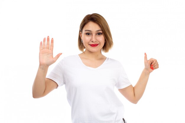 A front view young lady in white t-shirt posing smiling showing like sign on the white