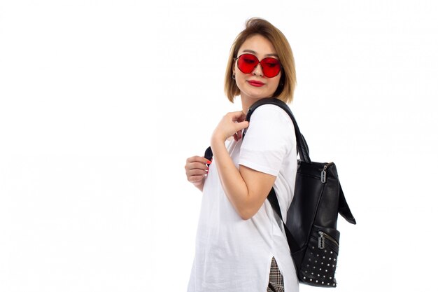 A front view young lady in white t-shirt red sunglasses black bag smiling on the white