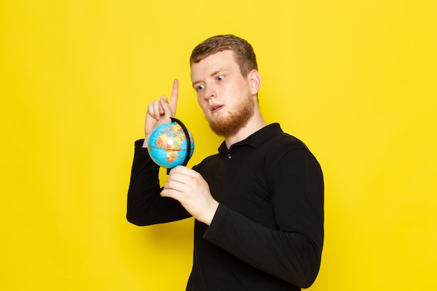 Free Photo front view of young male in black shirt holding little globe