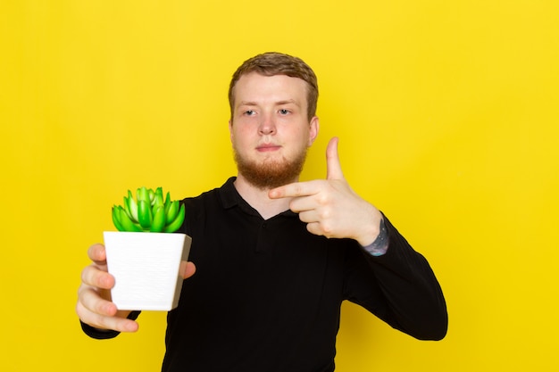 Free photo front view of young male in black shirt holding little green plant