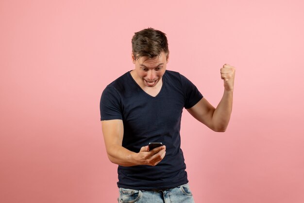 Front view young male in blue t-shirt using his phone on pink background man model emotion color male