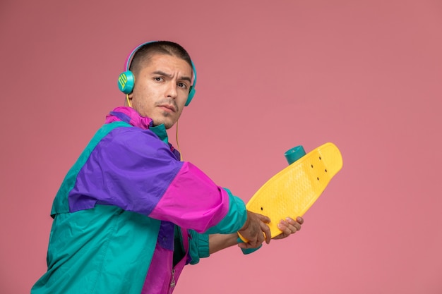 Free photo front view young male in colorful coat listening to music preparing to hit on pink desk