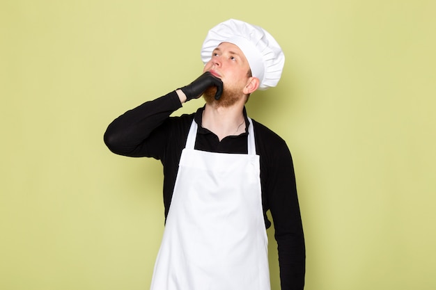 Free photo a front view young male cook in black shirt with white cape white head cap in black gloves posing thinking