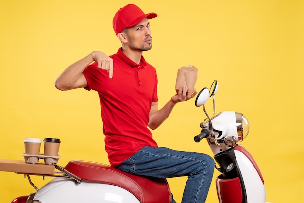 Front view young male courier in red uniform on a yellow background