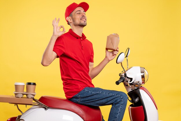 Front view young male courier in red uniform on a yellow background