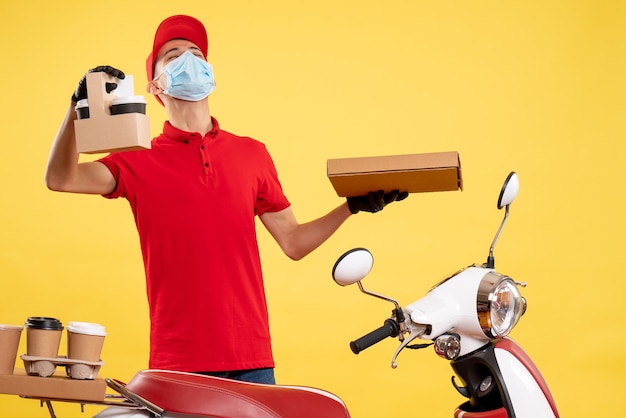 Free photo front view young male courier in uniform with coffee and food box on yellow background