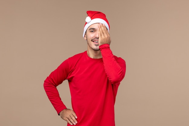 Front view young male covering half of his face on brown background emotions holiday male