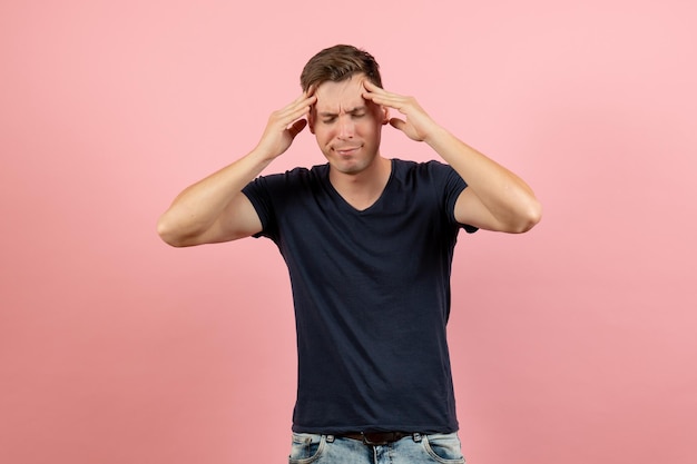 Front view young male in dark-blue shirt suffering from headache on pink background