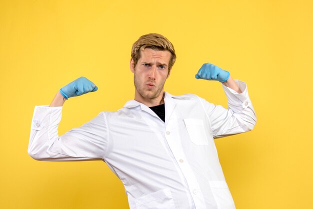 Free photo front view young male doctor flexing on yellow background human covid medic pandemic