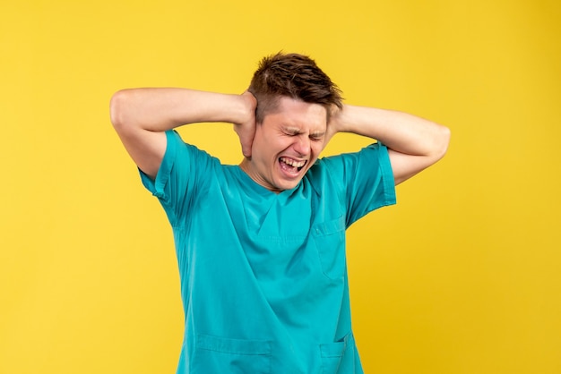 Free photo front view young male doctor in medical suit closing his ears on yellow background