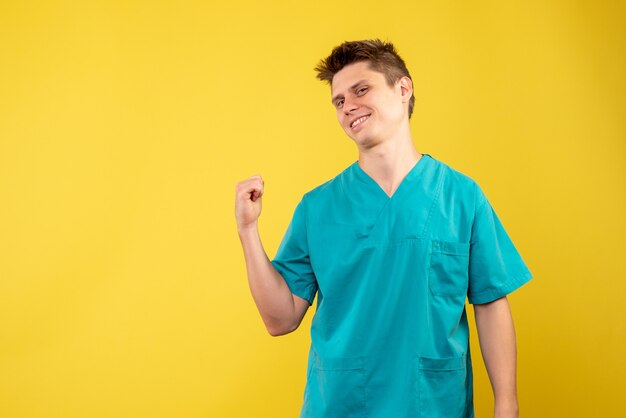 Front view young male doctor in medical suit on yellow background