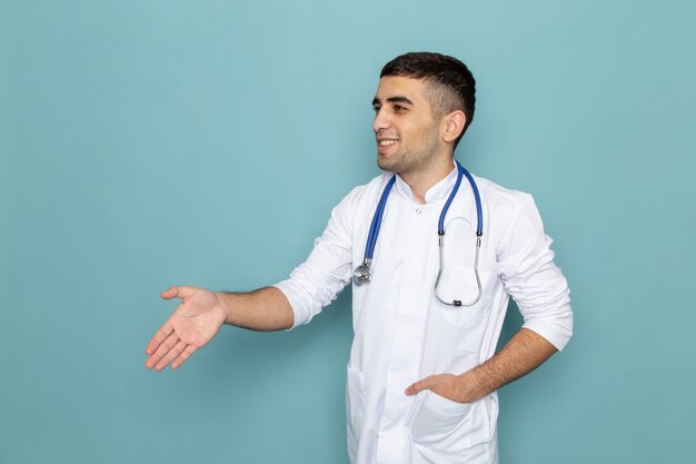 Front view of young male doctor in white suit with blue stethoscope shaking hands