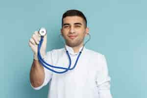 Free photo front view of young male doctor in white suit with blue stethoscope smiling