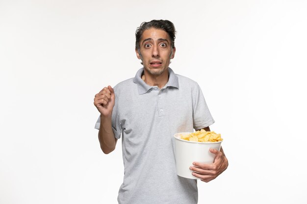 Front view young male eating potato chips watching movie on white desk