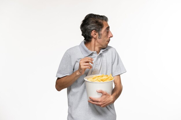 Front view young male eating potato chips and watching movie on white surface