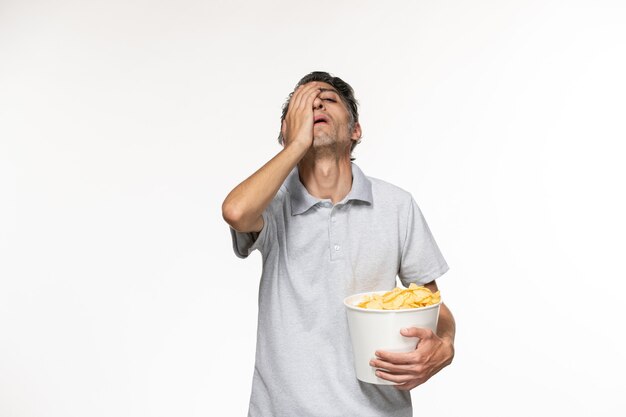 Front view young male eating potato chips while watching movie on white desk