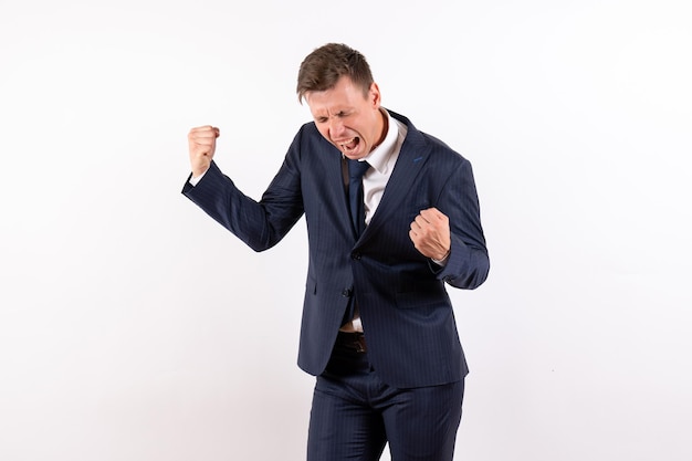 Front view young male in elegant classic suit emotionally rejoicing on white background