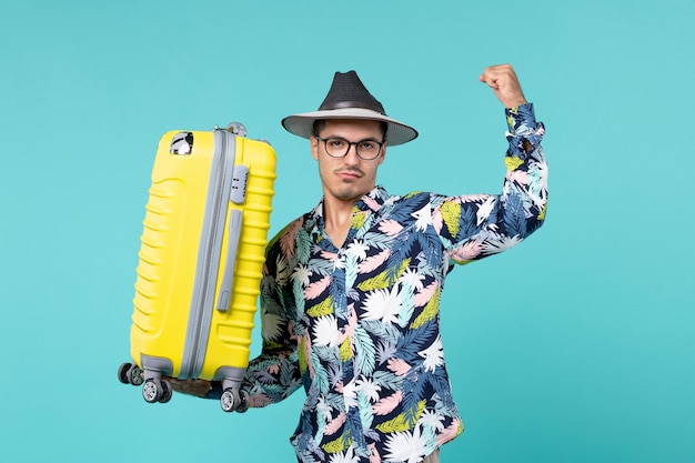 Front view young male going in vacation and holding his yellow bag on blue desk